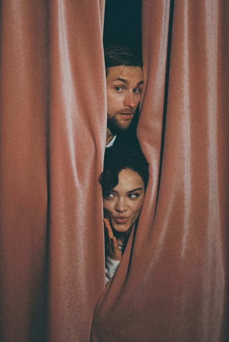 Couple peeking out from behind the booth curtain