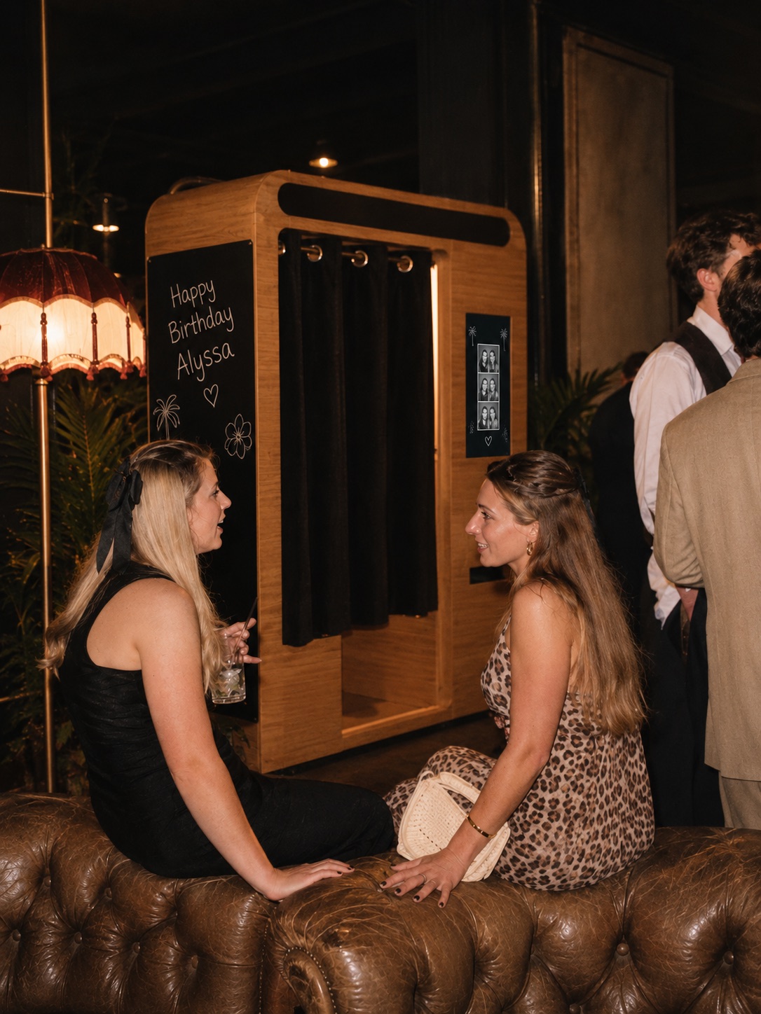 Guests chatting by a birthday-themed photo booth