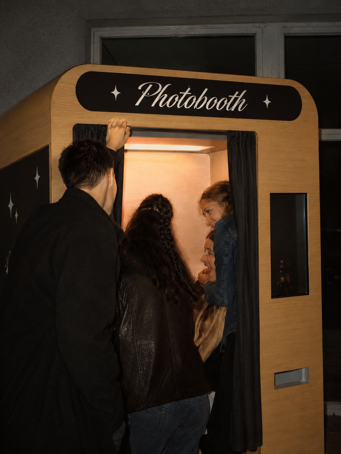Friends stepping into a neon-signed photobooth together