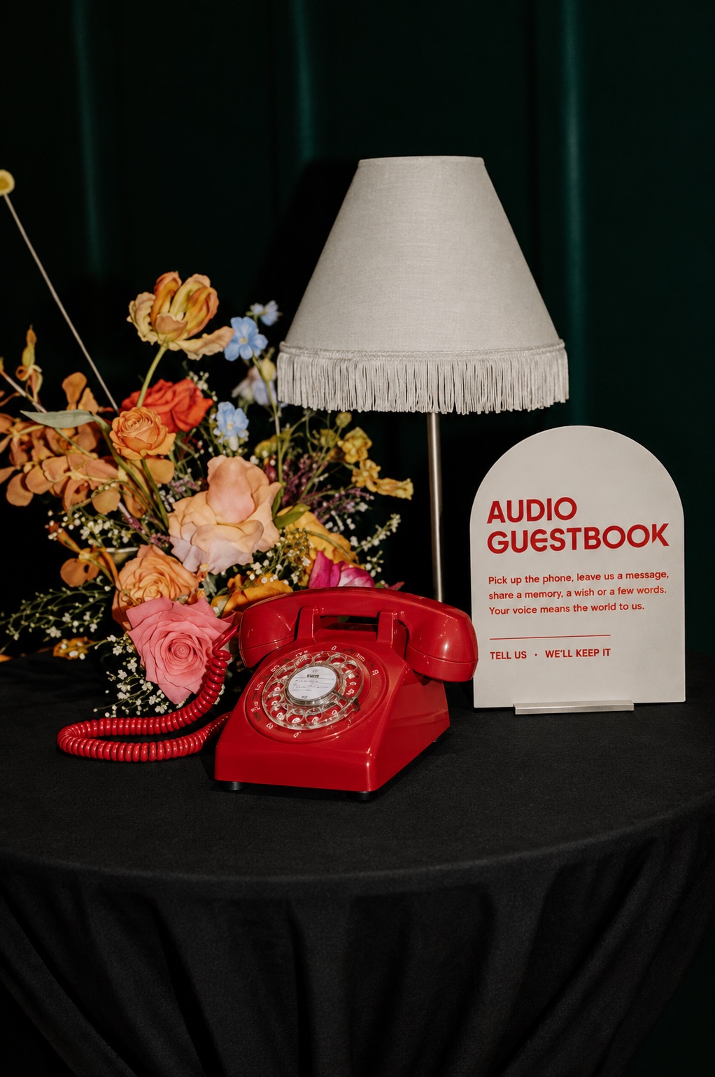Vintage red rotary phone beside an Audio Guestbook sign