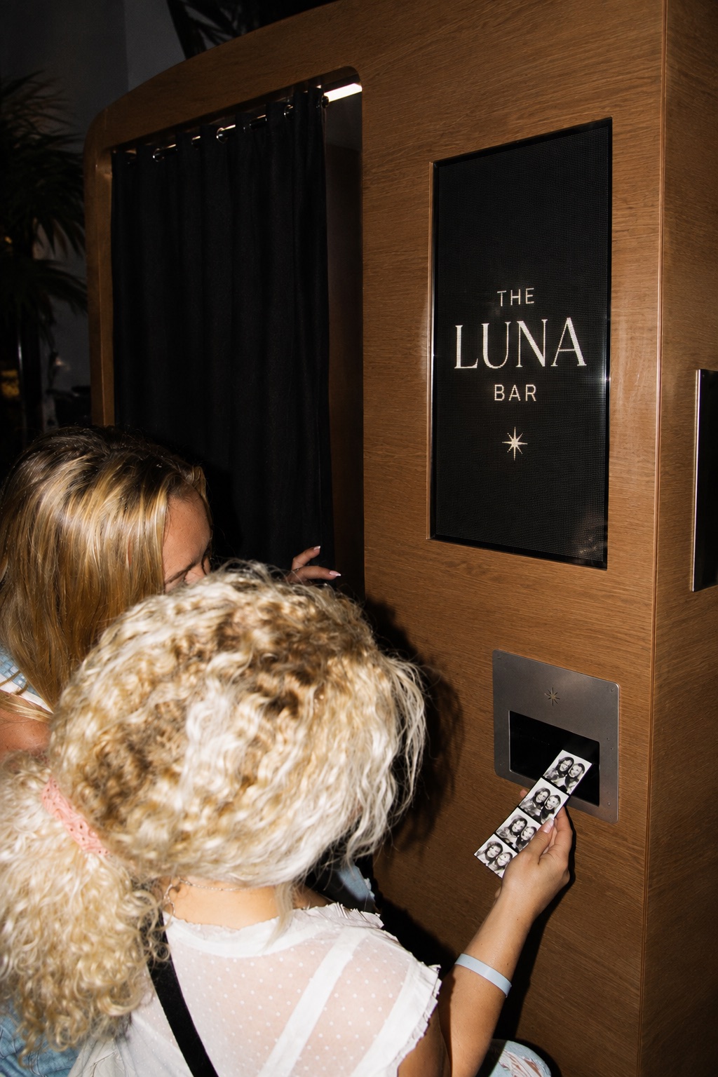 Guests picking up printed photo strips at The Luna Bar's branded booth
